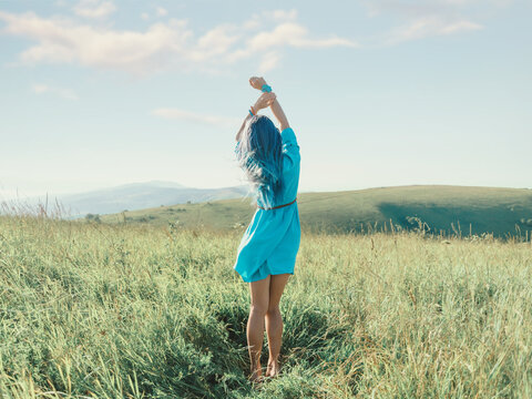 Romantic Blue Hair Woman Standing With Hands Up In Summer Meadow.