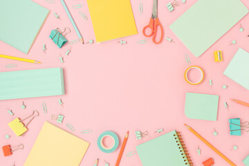 Border frame made of office supplies on a pink pastel background. Back to school concept with place for text.