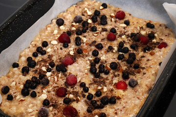 Vegetarian fruit unbaked pizza dough with berries and almonds. Fresh pizza in a casserole at home kitchen. Vegetarian food concept. Close up, selective focus and top view