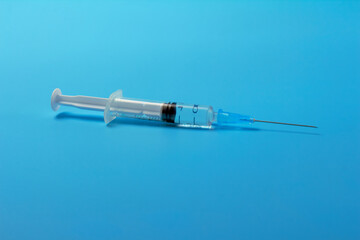 A syringe with a vaccine on a blue background