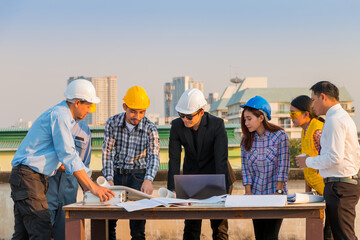 Engineer and worker team talking about project with construction site and cityscape background.