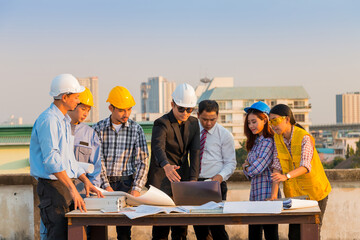 Engineer and worker team talking about project with construction site and cityscape background.