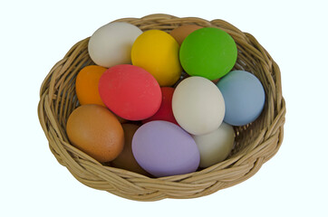 Fototapeta na wymiar Woven rattan basket of colored eggs on white background