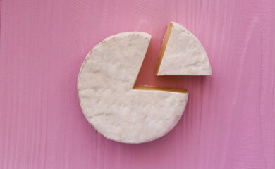 delicate camembert cheese on a pink background