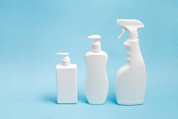 several white plastic bottles with different types of dispensers on a blue background, two white unbranded dispenser bottles and a spray bottle