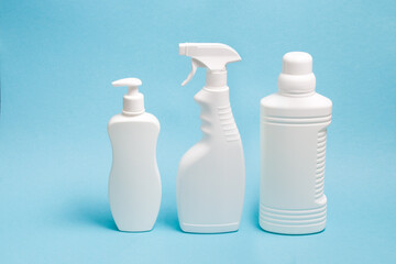 several white plastic bottles with various types of dispensers on a blue background, white unbranded dispenser bottle, spray bottle and a large bottle without a label