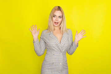 Attractive blonde woman in plaid jacket dress over yellow background