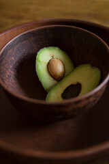 Fresh green tasty avocado lies in clay natural dishes on a wooden oak table
