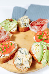 Blue cheese bruschette snack on a wooden plate on a white wooden table and gray napkin. Mini sandwich mix