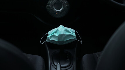 Surgical or medical mask is putting on a car automatic gear for preparing to go outside during covid19 pandemic, the concept of protection against bacteria and viruses
