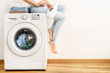 Young woman washing with washing machine