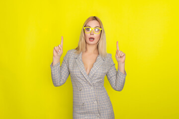 Attractive blonde woman in plaid jacket dress over yellow background