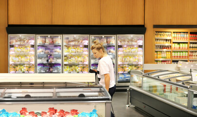 Woman choosing frozen food from a supermarket freezer	
