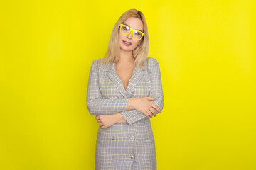 Attractive blonde woman in plaid jacket dress over yellow background