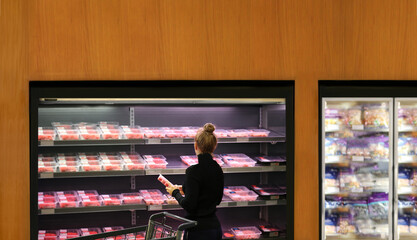 Woman purchasing a packet of meat at the supermarket	