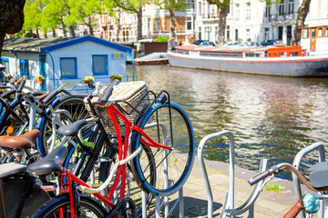 Fototapeta na wymiar Bicycles parking lot in Amsterdam, Netherlands against a canal during summer sunny day. Amsterdam postcard iconic view. Tourism concept.
