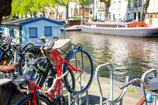 Bicycles parking lot in Amsterdam, Netherlands against a canal during summer sunny day. Amsterdam postcard iconic view. Tourism concept.