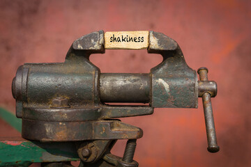 Vice grip tool squeezing a plank with the word shakiness