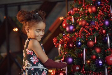 Merry Christmas! Cute little child girl is decorating the Christmas tree.