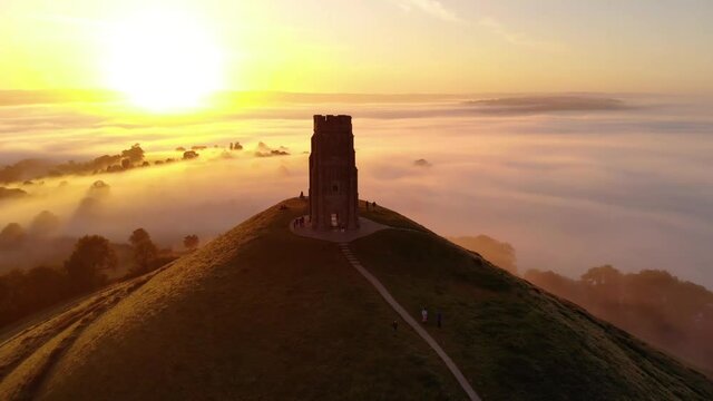 Orbiting the morning sunrise over Glastonbury Tor and the misty fields, Somerset.