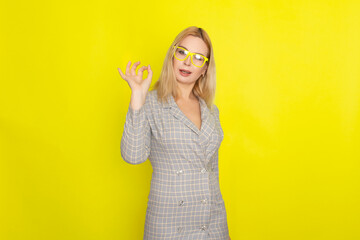 Attractive blonde woman in plaid jacket dress over yellow background
