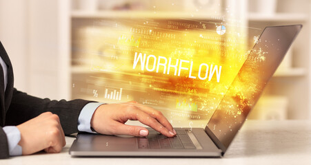 Closeup of businessman hands working on laptop with WORKFLOW inscription, succesfull business concept