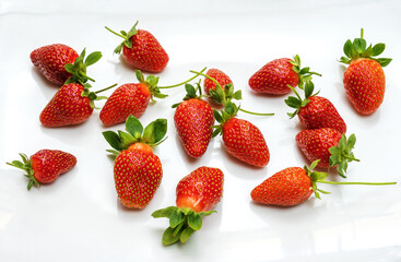 Fresh strawberries scattered on glossy white surface