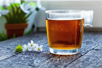 Cup of tea and wildflowers on a textured wooden surface.