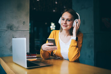 Young woman updating playlist on media application 