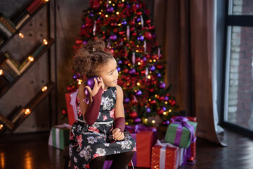 Merry Christmas! Cute little child girl is decorating the Christmas tree.