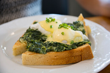 Traditional Eggs Benedict Florentine with poached eggs. creamed spinach, green onions, Hollandaise sauce and nutmeg, over a brioch bread