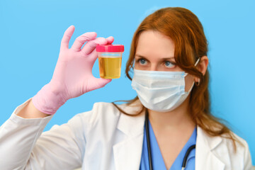 Woman nurse with a can of urine for analysis on a blue background, closeup face.