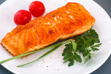 Salmon fillet with vegetable on white plate. Gray background