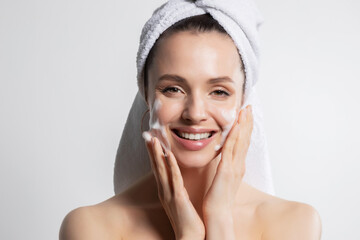 Smiling  woman in towel applying cosmetic foam portrait. 
