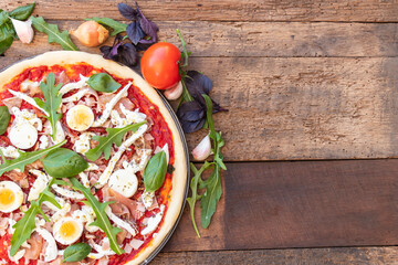 Top view of pizza Italian dish mediterranean food with ham, basil and Rocket green leaves, mozzarella on top with wooden background with copy space.