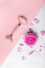 Creative shot of jade roller and pink rose on pink background. Copy space. © chichkaua