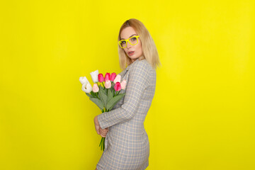 Blonde woman in plaid dress holding tulips bouquet