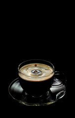 a Cup of coffee with a falling drop on a black background
