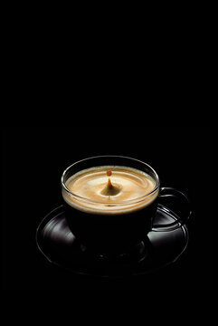 a Cup of coffee with a falling drop on a black background