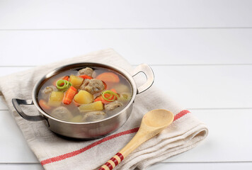 Homemade Warm Vegetable Meatball Soup, Served on White Bowl with Wooden Spoon