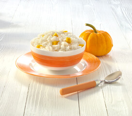 a bowl of rice porridge with milk and pumpkin on the table