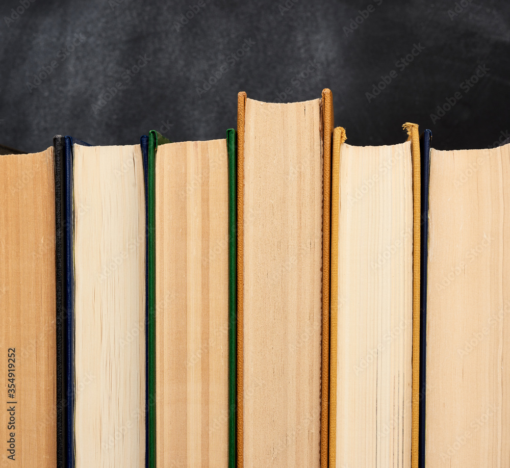 Aufkleber stack of various books on the background of an empty black chalk board