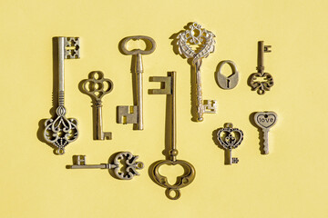 Multiple vintage keys isolated on a yellow background. Image of old antique keys,  top view, flat lay