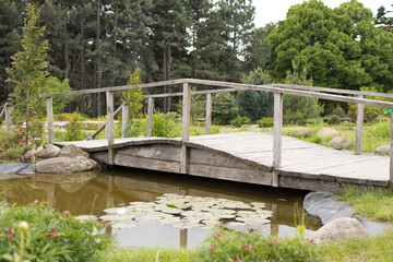Naklejka premium Wooden bridge over a pond with lilies and lotuses, landscape design