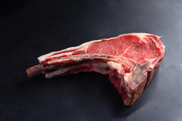 Classic raw bone steak on black background. Close-up