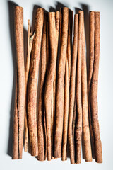 top vertical view on heap of dry cinnamon sticks served on white table surface