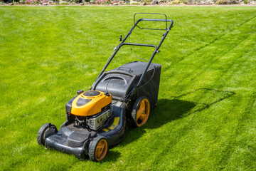 Lawn mower on fresh green lawn, freshly cut grass on summer sunny day