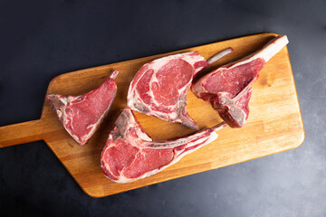 assorted raw steaks on a wooden board. Black background