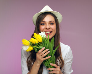 Happy woman wearing hat holding flowers.