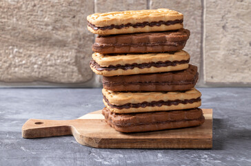 A stack of chocolate and milk cookies lying on a wooden plank.